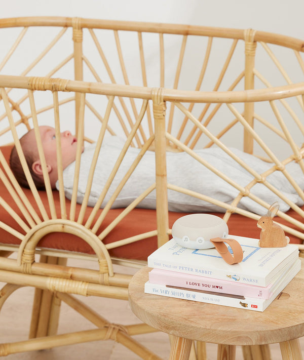 ergoPouch Drift Away White Noise Machine Taupe on top of baby books near cot